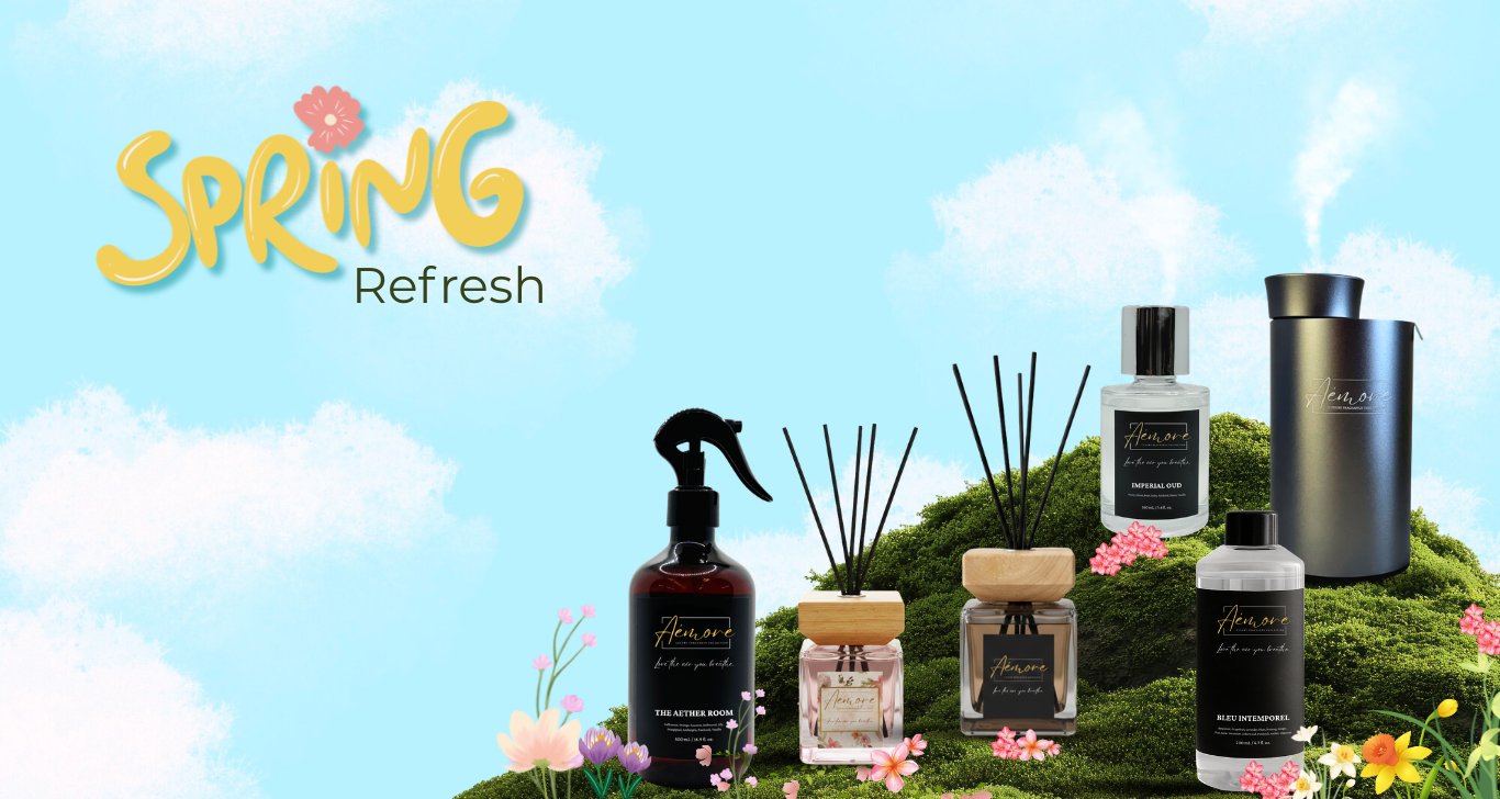 Collection of reed diffuser bottles and diffusers on a grassy patch with flowers against a blue sky.